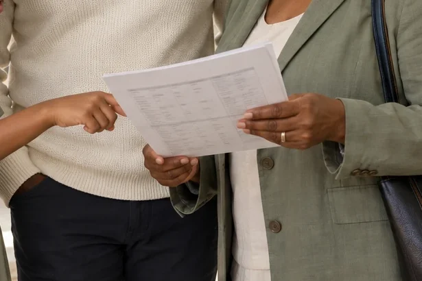 A child pointing at a printed plan while two adults read it with her
